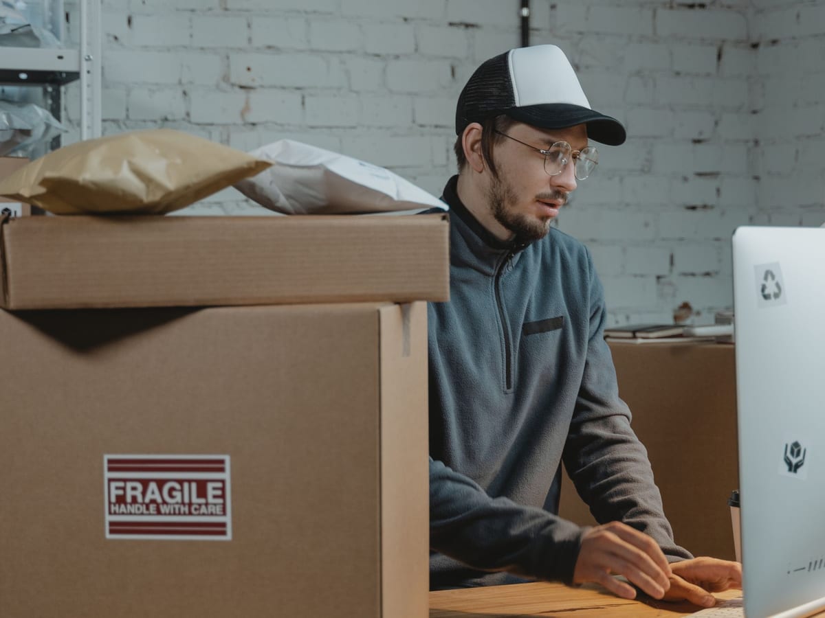 A team member processing webstore orders at a computer beside outgoing packages